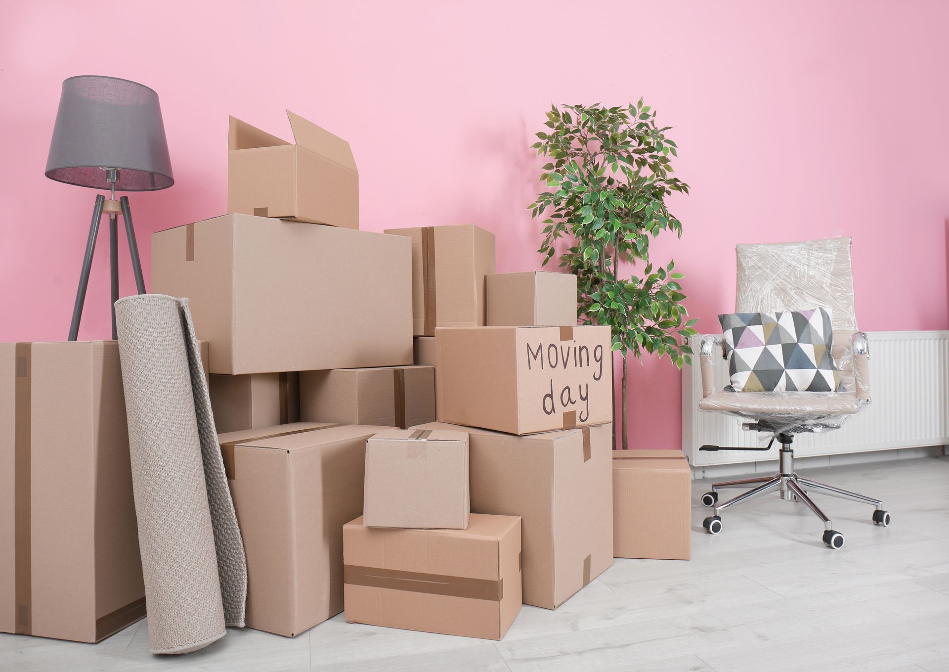 A pile of cardboard boxes in a room with a pink wall.