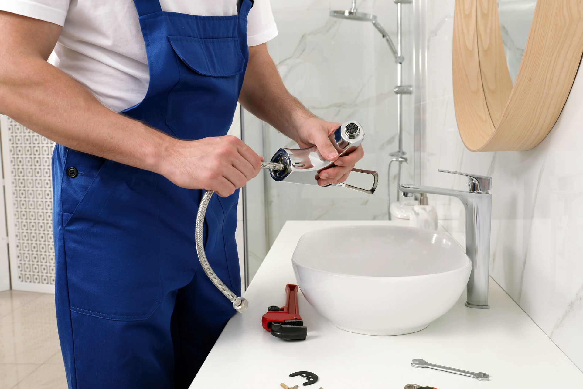 A plumber is fixing a sink in a bathroom.