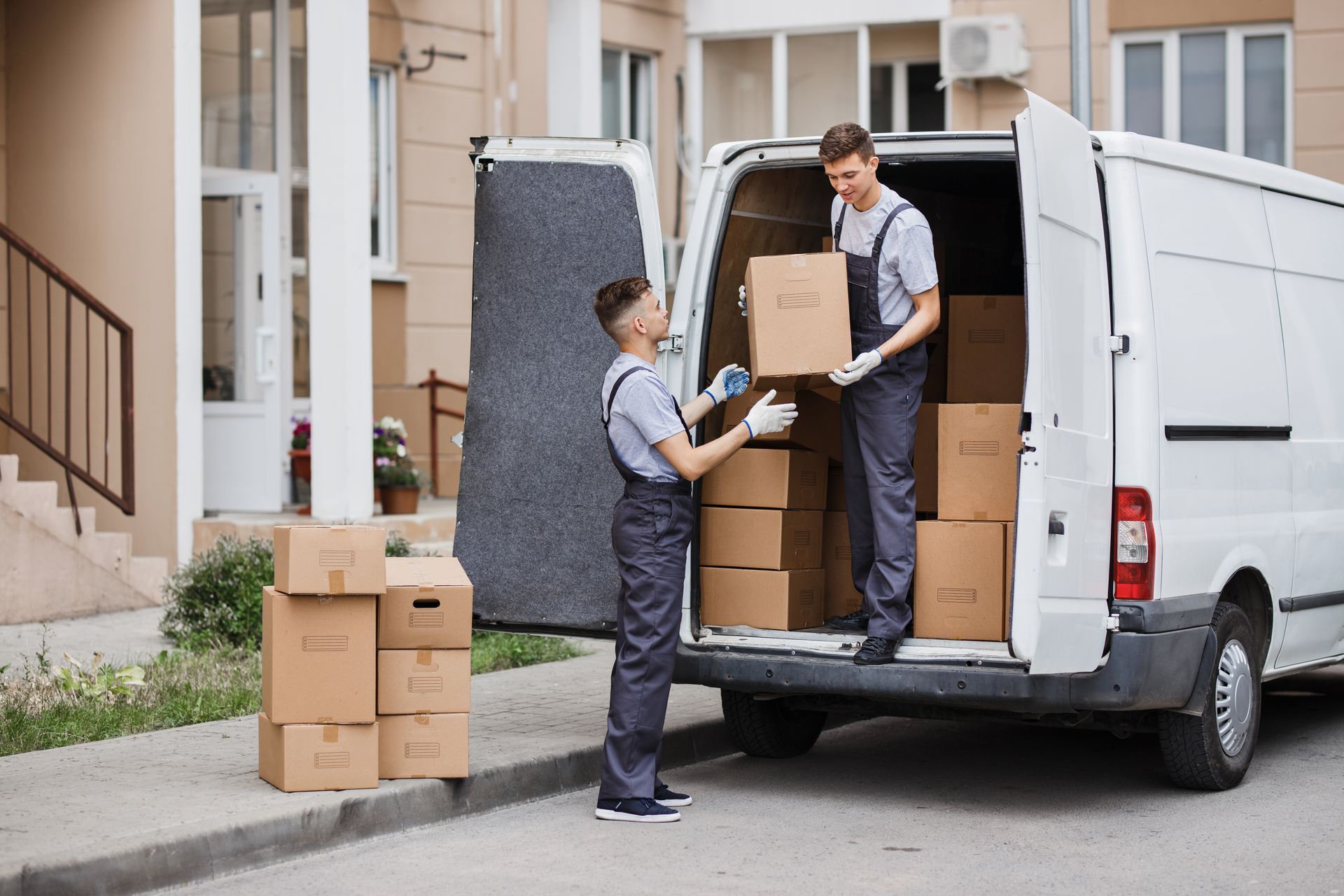 Two men are loading boxes into a white van.