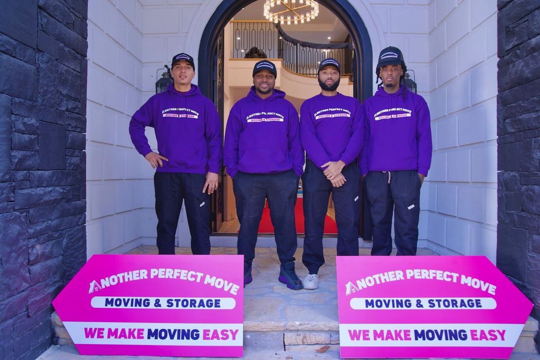 A group of men wearing purple sweatshirts are standing in front of a building.