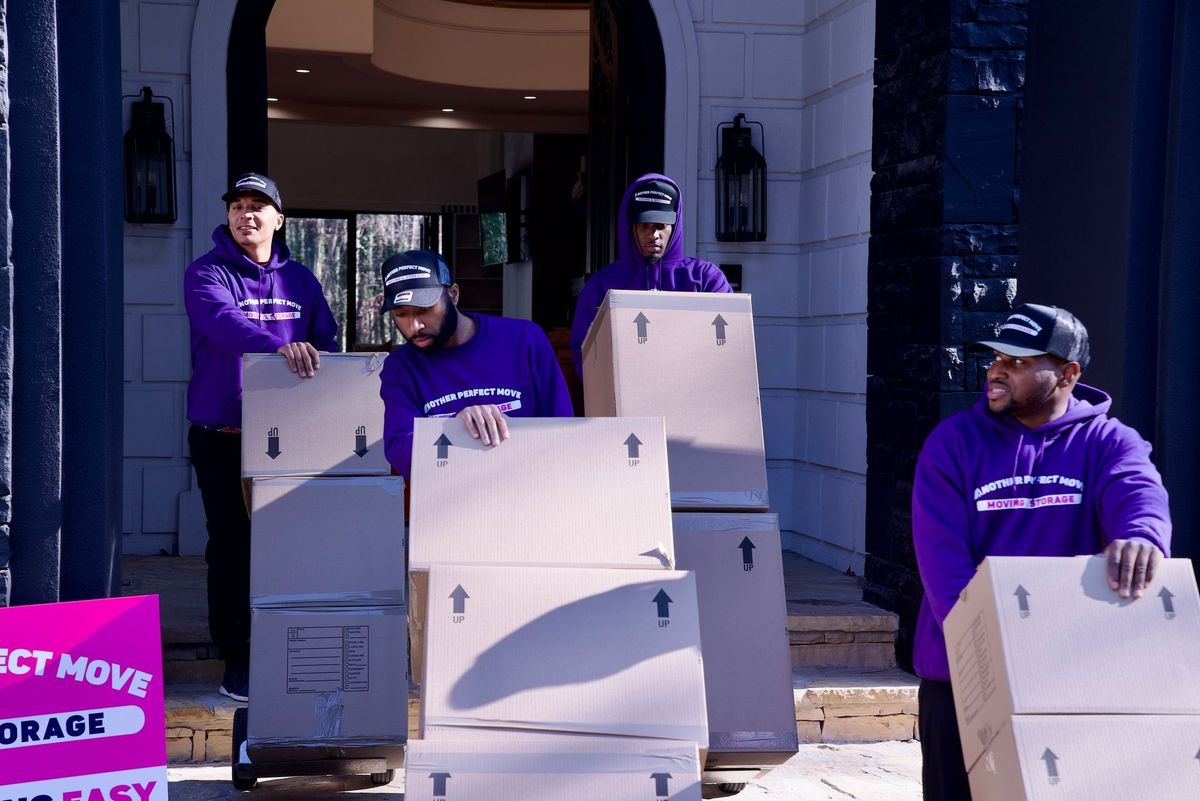 A group of men are carrying boxes in front of a house.