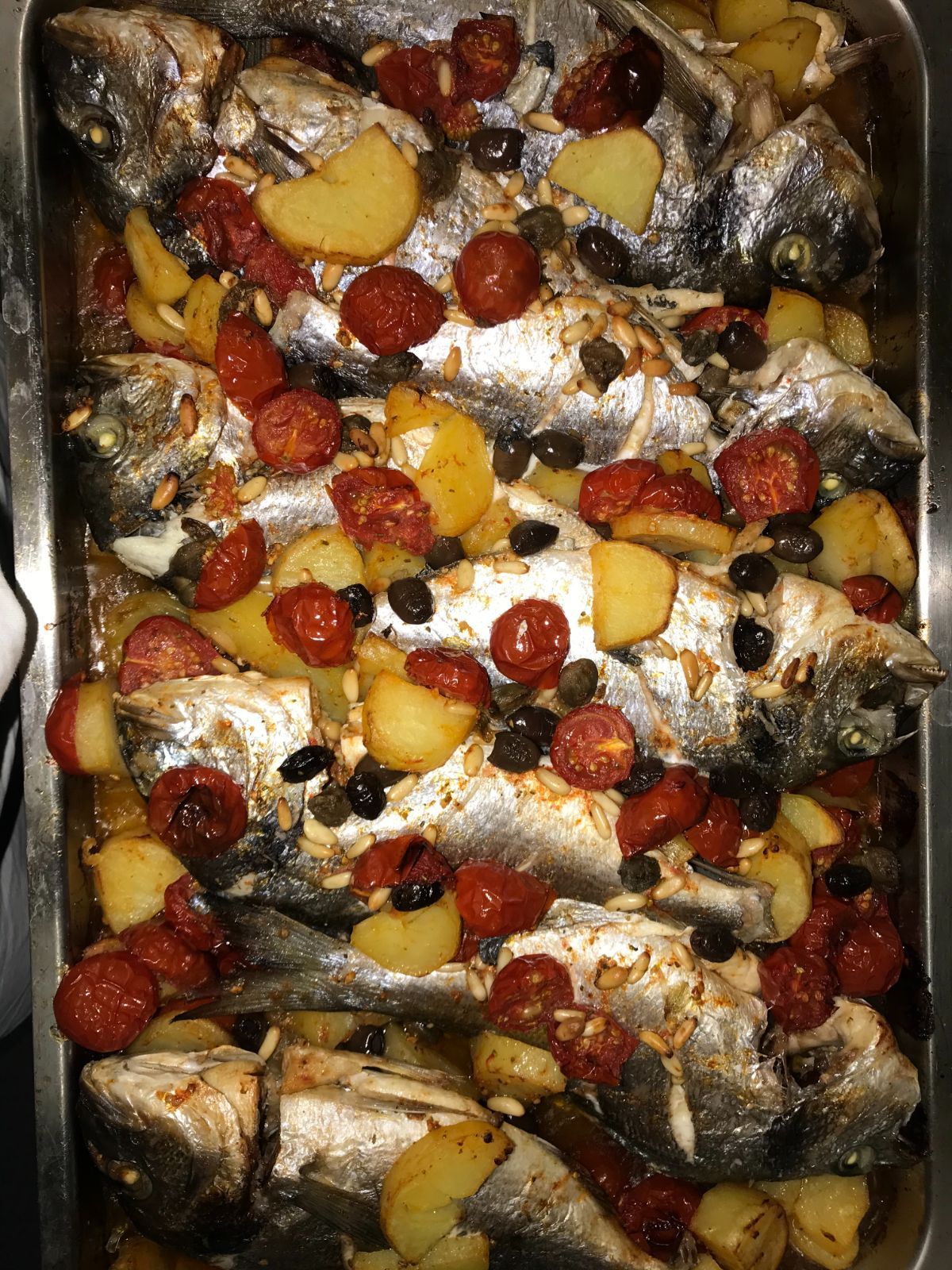 pesce al forno con olive, patate e pomodorini
