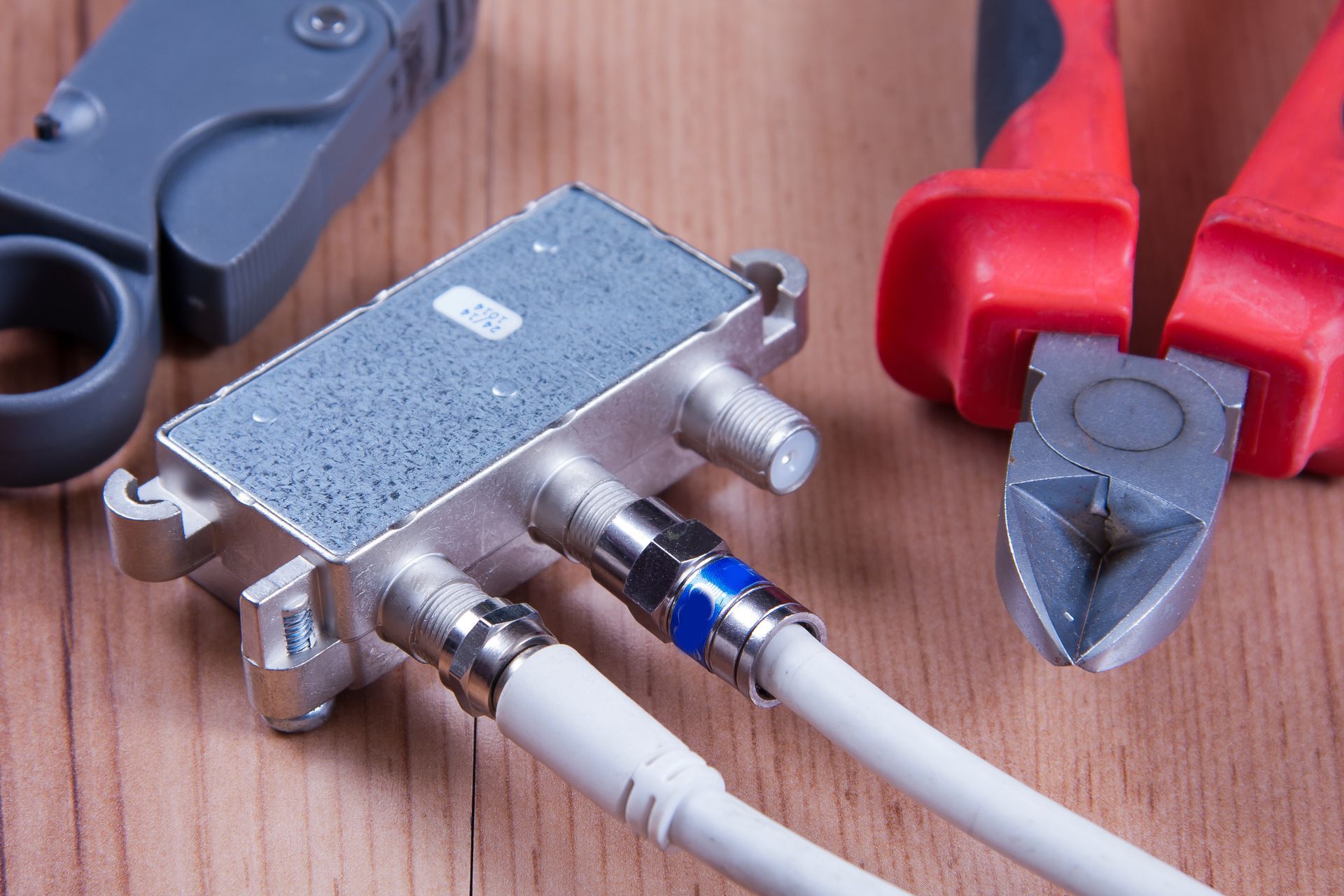 A pair of pliers and a cable splitter on a wooden table