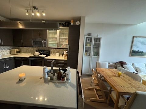 Modern kitchen with island, adjacent dining area, and living room.