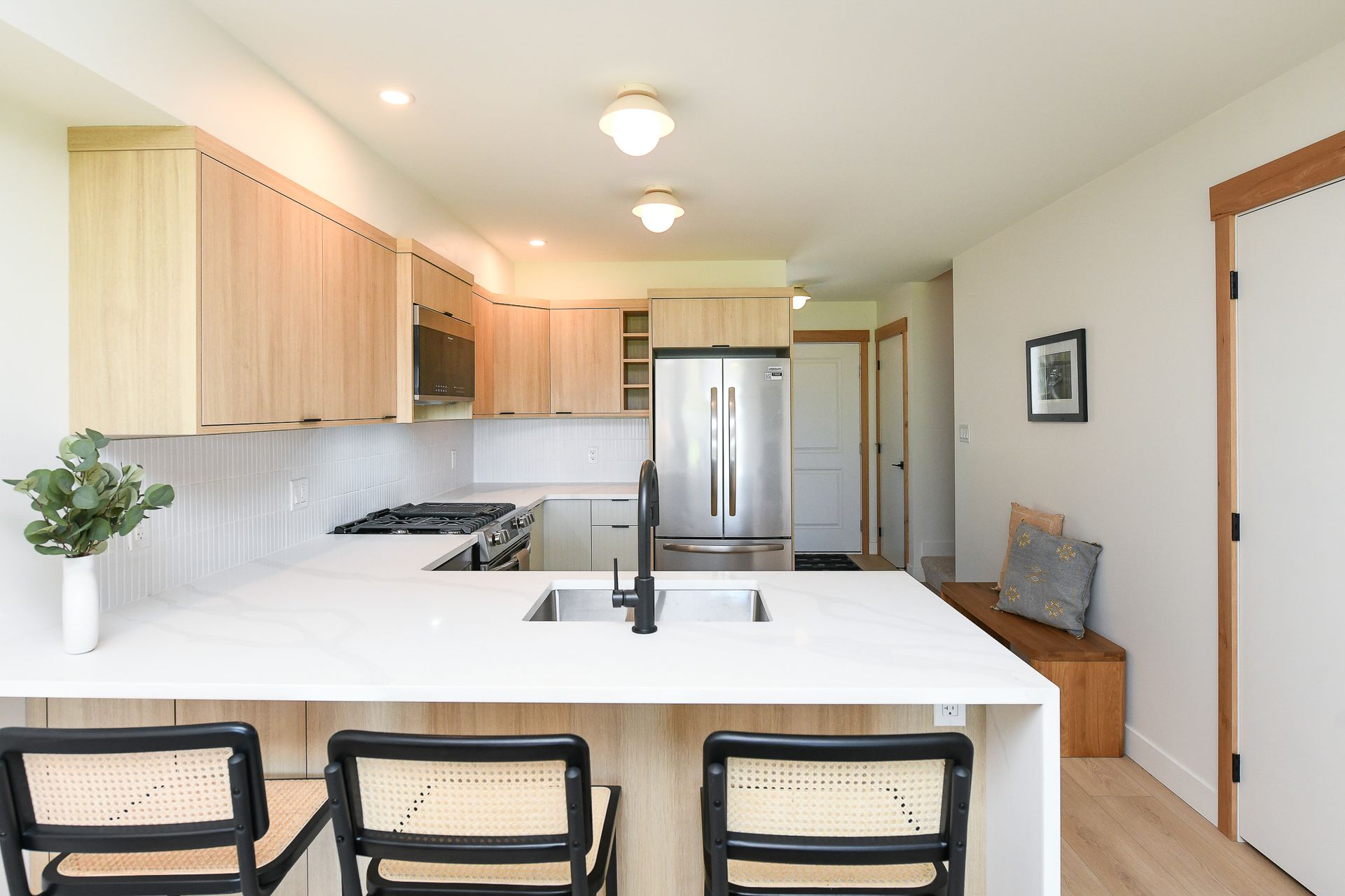 A kitchen with a sink , stove , refrigerator and stools.