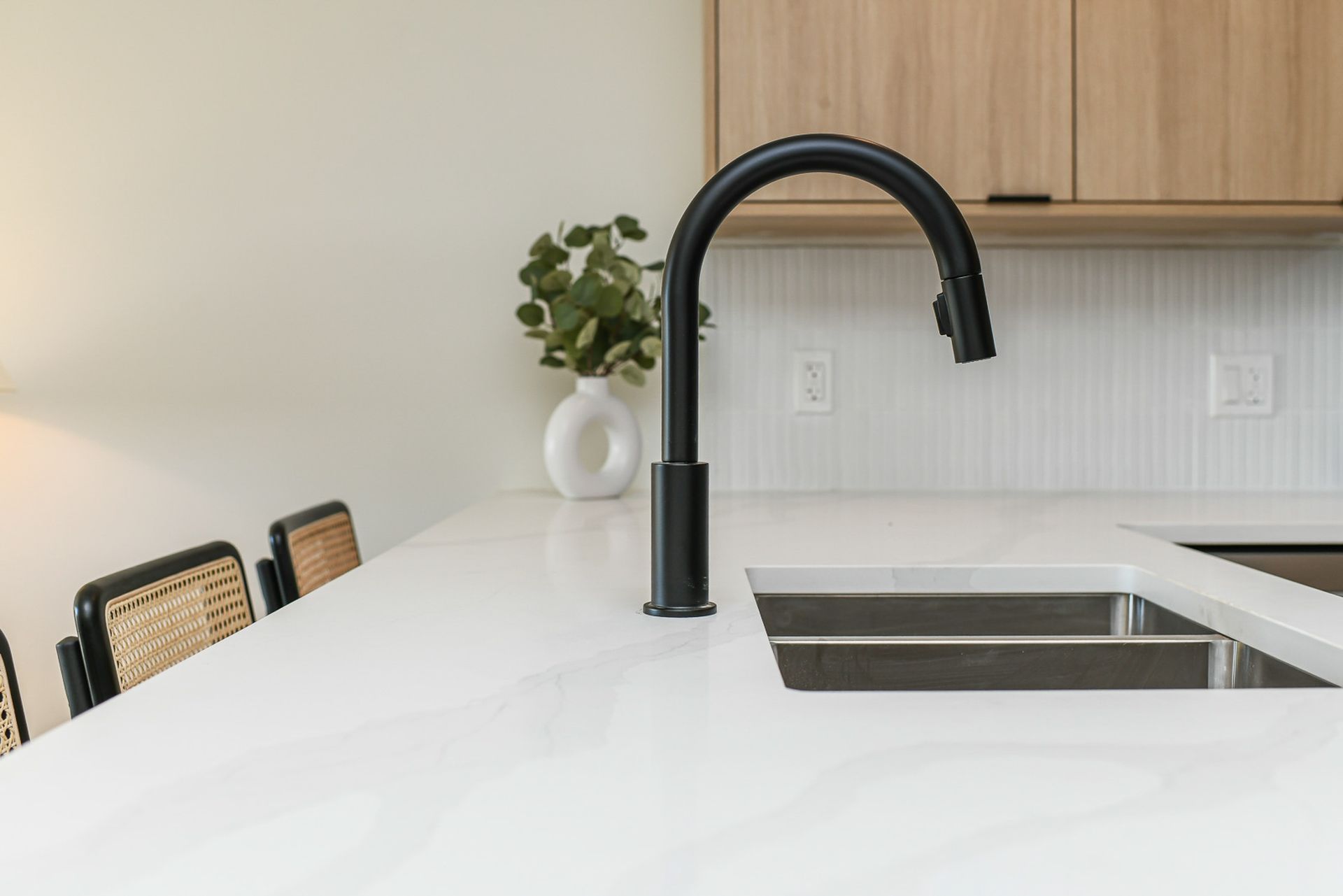 A kitchen sink with a black faucet on a white counter top.