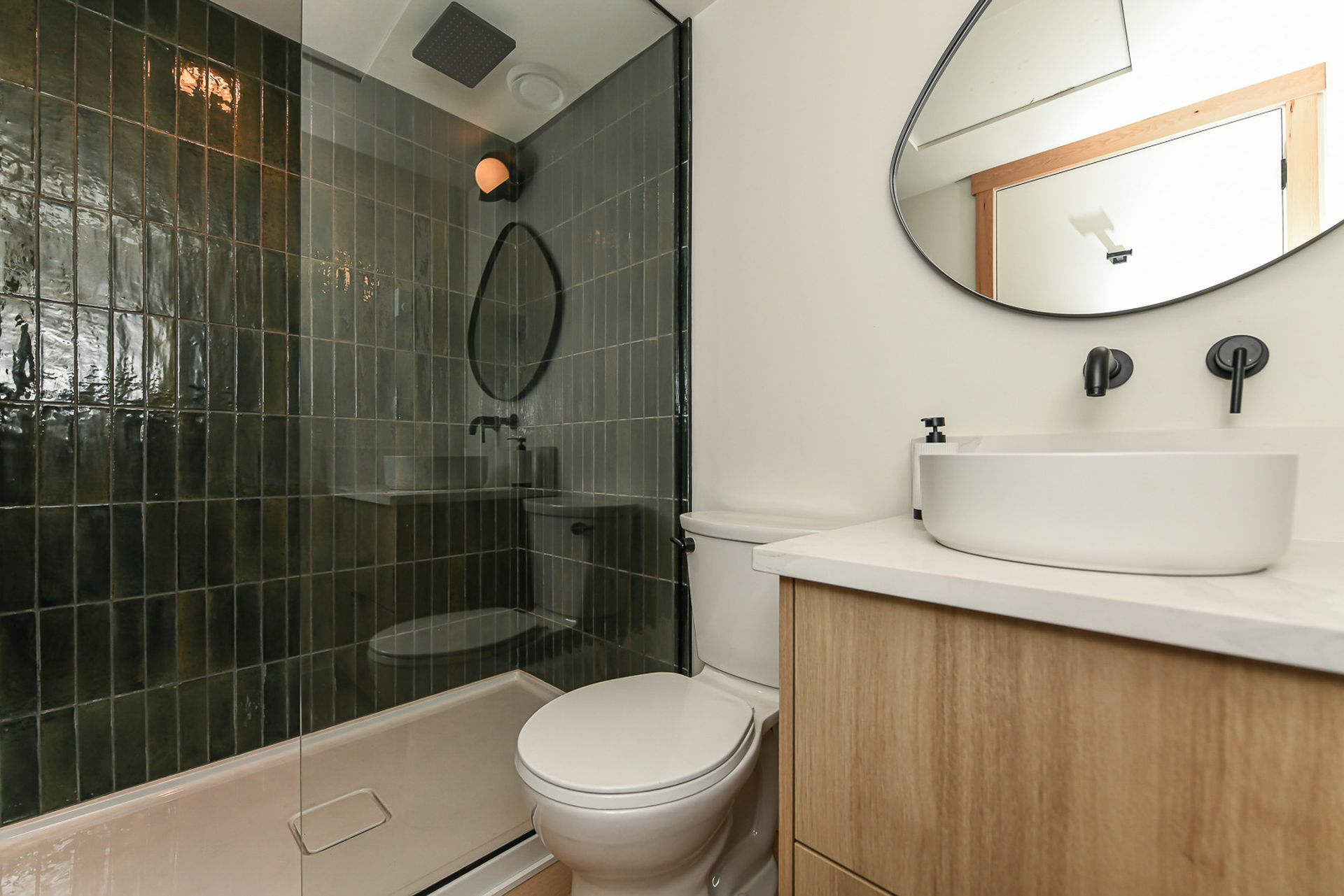 A bathroom with a toilet , sink and shower.