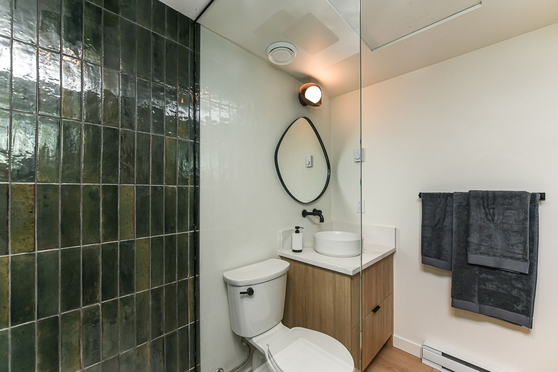 A bathroom with a toilet , sink , mirror and walk in shower.