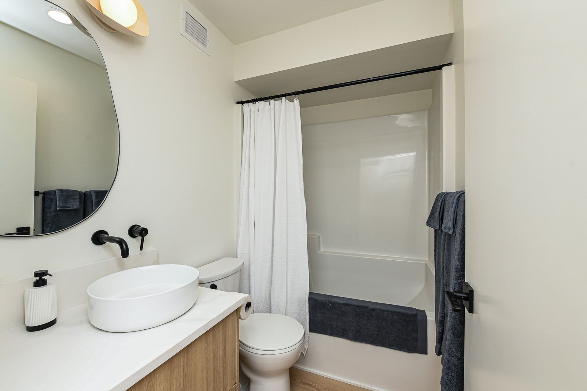 A bathroom with a toilet , sink , mirror and bathtub.