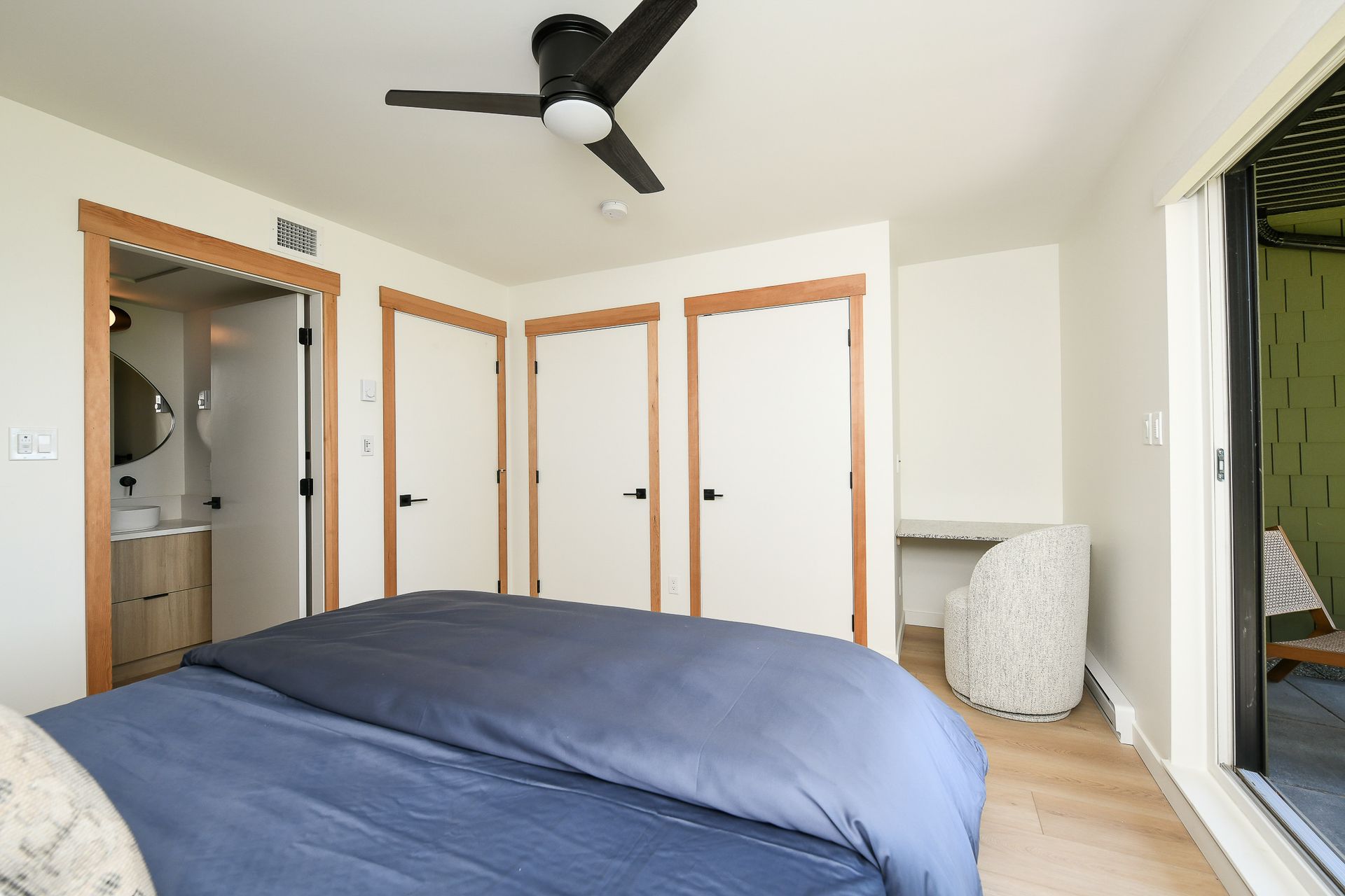 A bedroom with a bed , chair , ceiling fan and closets.