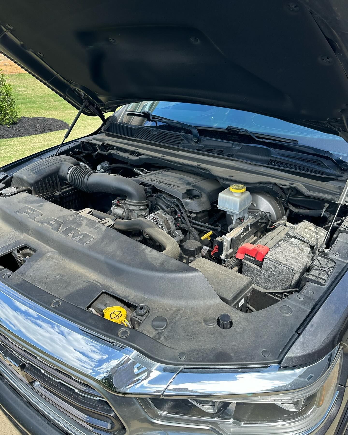 Open hood of a black RAM truck, revealing the engine compartment.