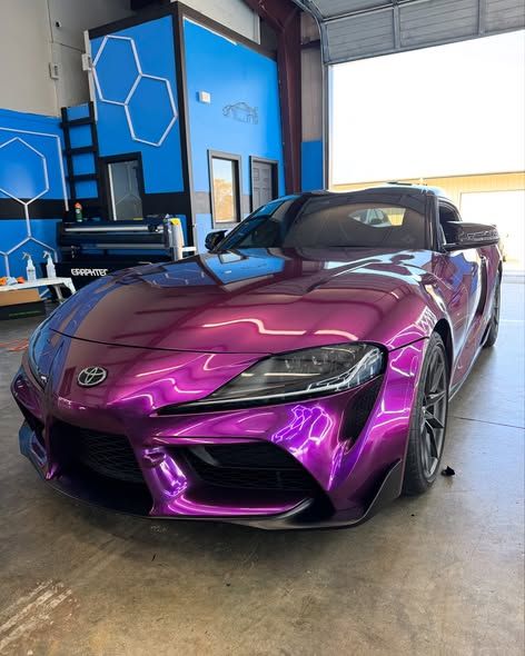 Purple Toyota Supra sports car inside a garage with blue and white wall accents.