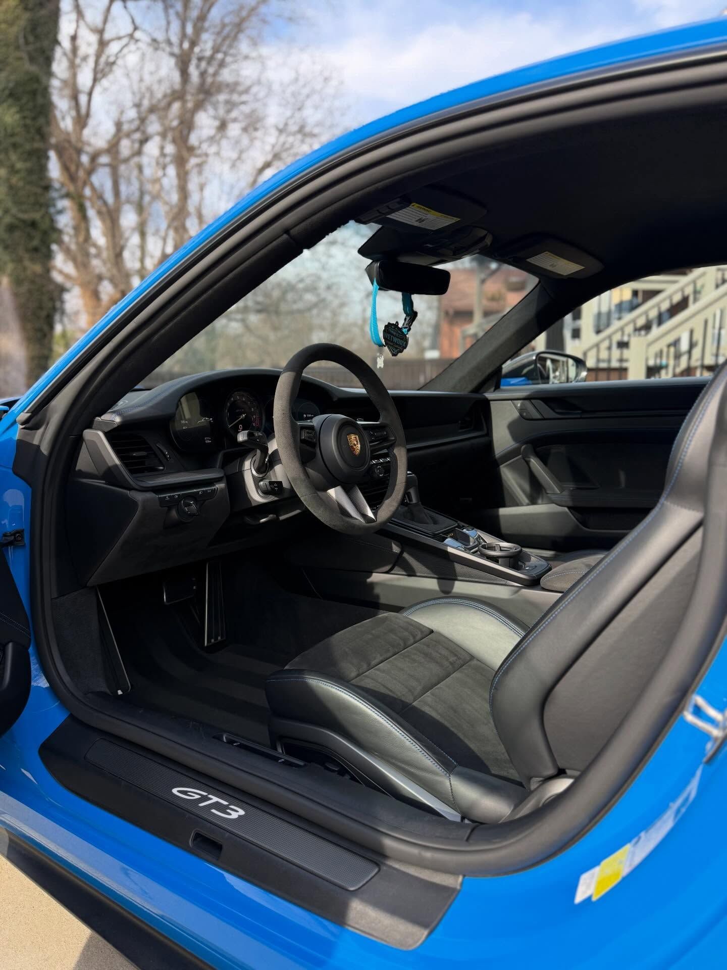 Blue Porsche GT3 interior with black seats, steering wheel, and dashboard.