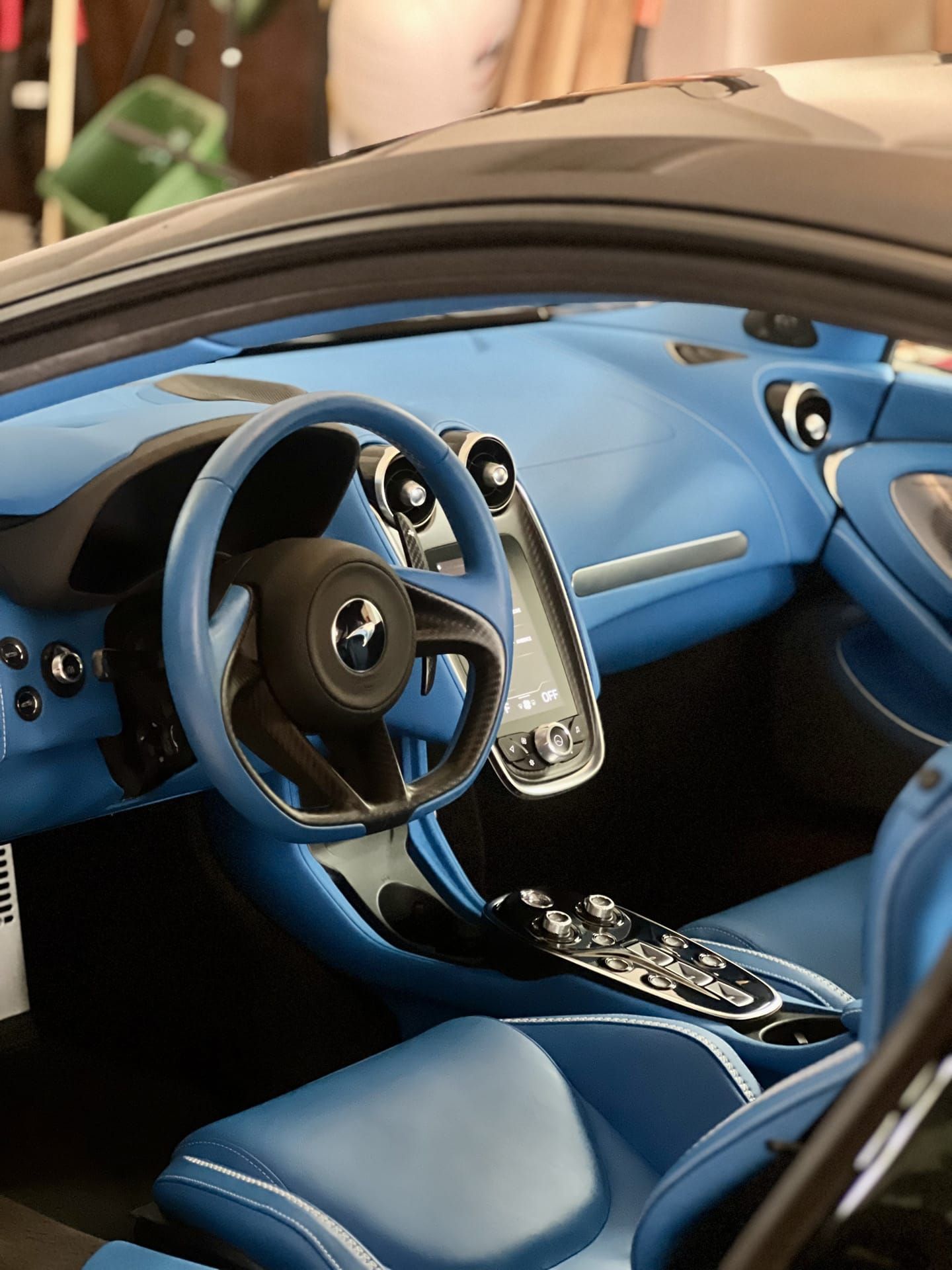 Interior view of a blue McLaren sports car, featuring a blue steering wheel, dashboard, and seats.
