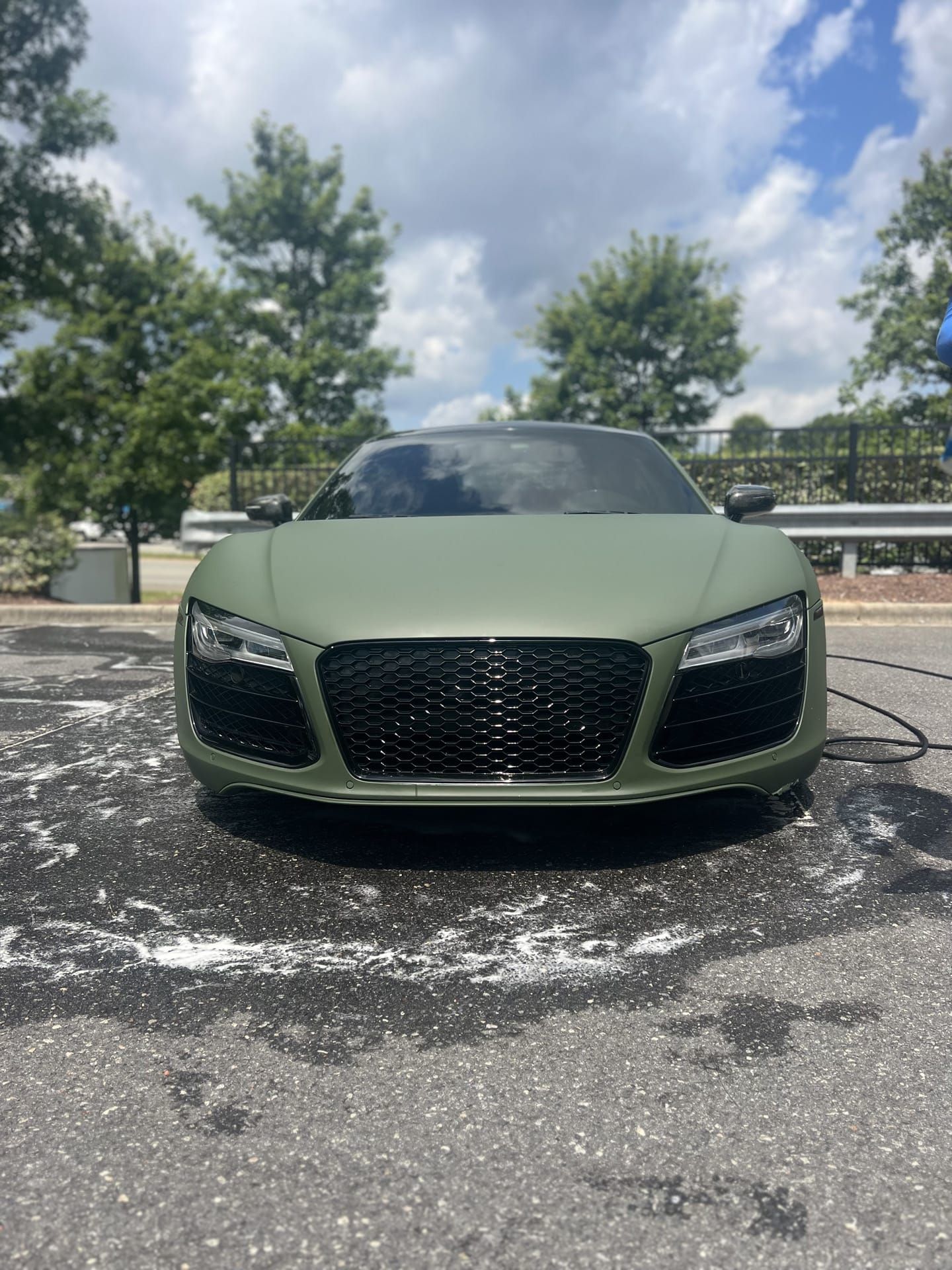 Green Audi R8 sports car, matte finish, parked outside on a sunny day.