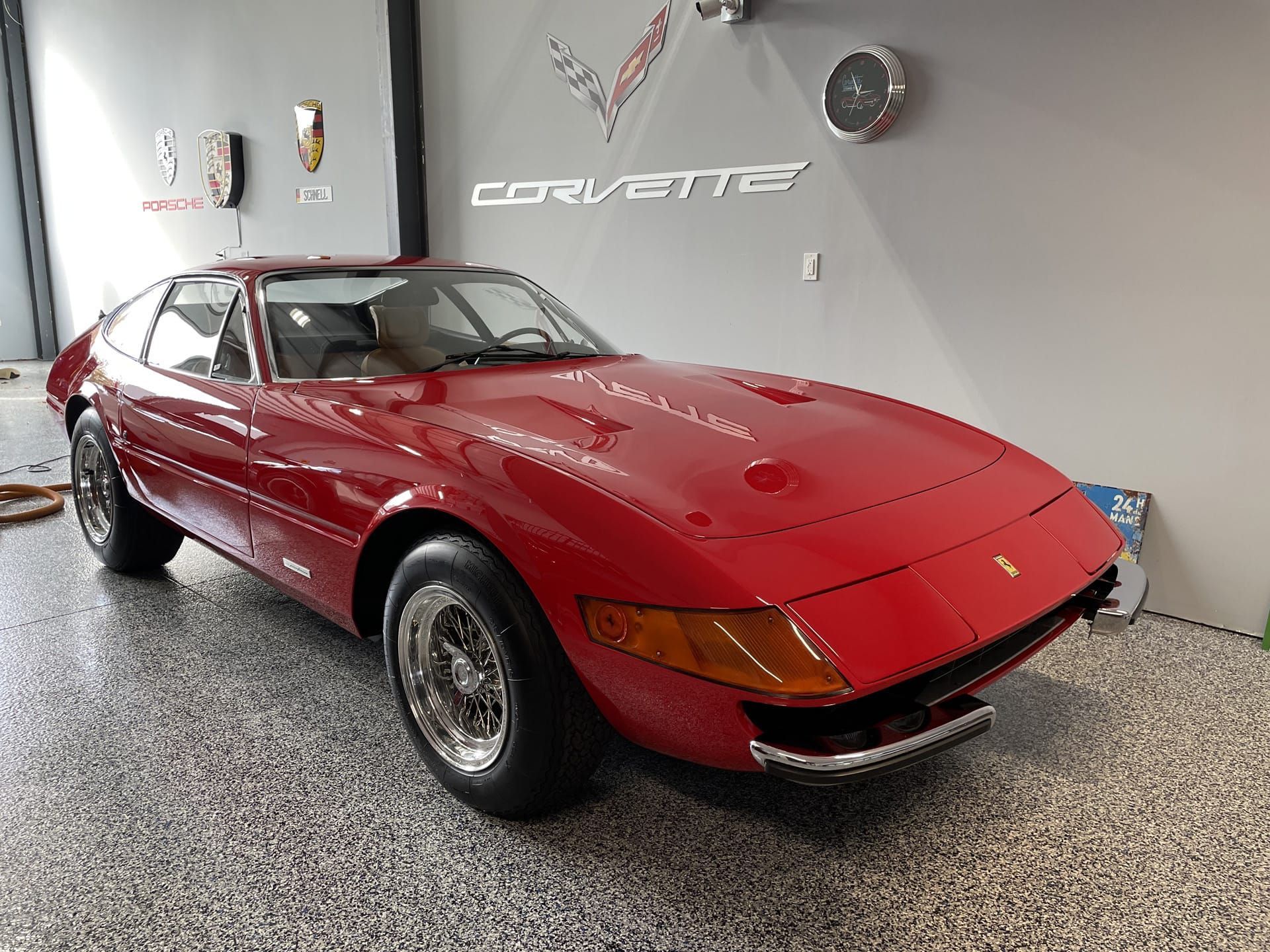 Red Ferrari Daytona sports car parked in a garage with a 