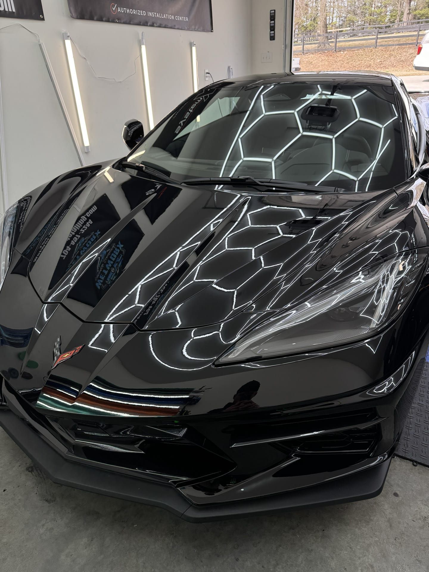 Black sports car with reflective surface under shop lights.