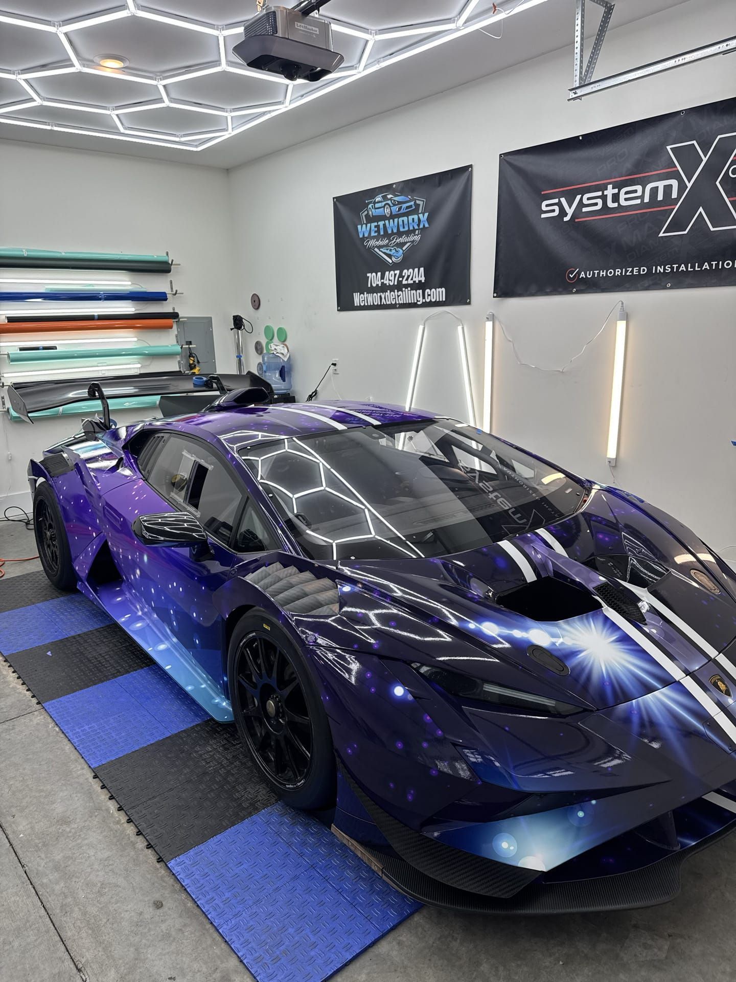 Lamborghini with custom galaxy wrap, in a shop, with white stripes and black rims.