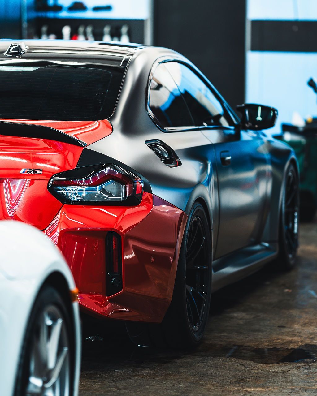 Red and black sports car with a matte finish parked in a garage.