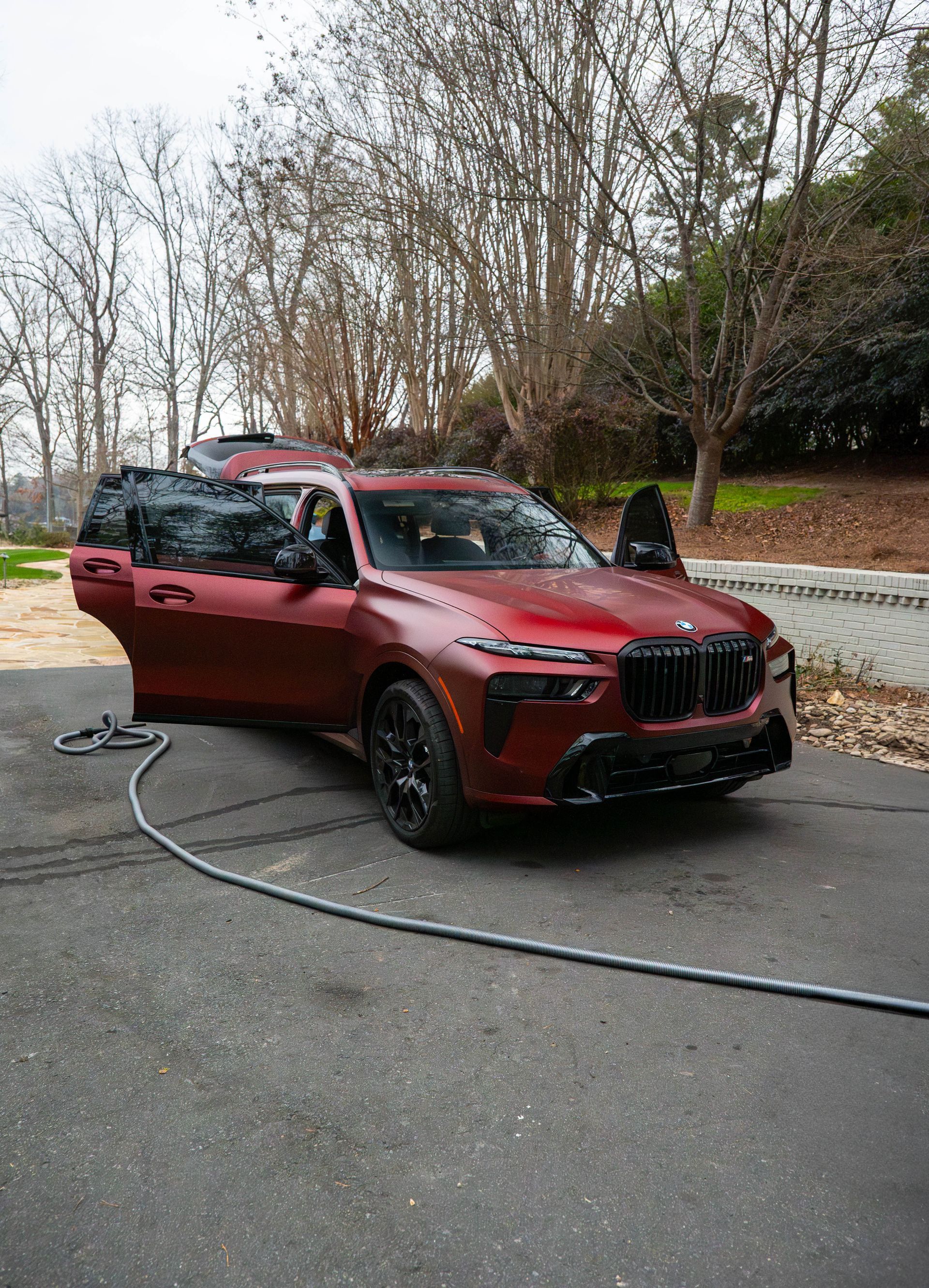 Red SUV with open doors on a paved driveway; a person is inside.