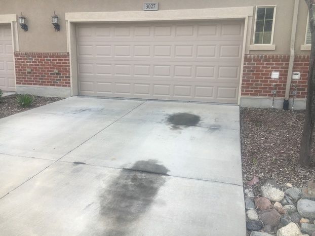 A concrete driveway in front of a garage door with a brick wall.