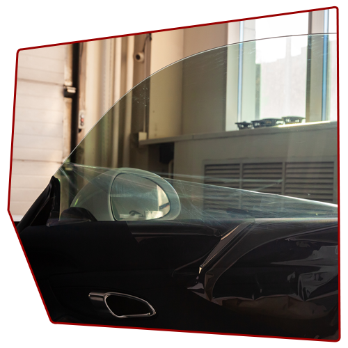 Car door window partially open, showing interior, side mirror, and building exterior visible.