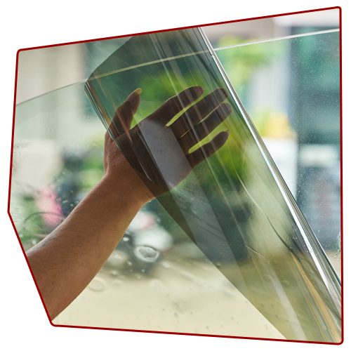 Hand holding and applying window tint to a glass pane.
