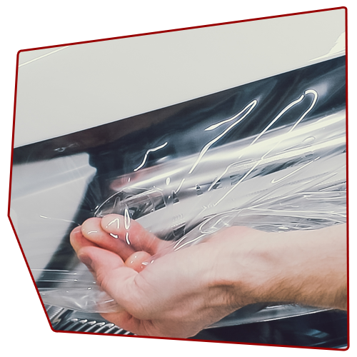 Hand reaching for clear plastic wrap on a machine.