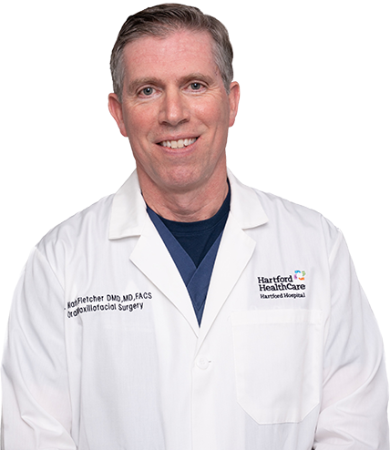 A man wearing a white lab coat that says harvard healthcare
