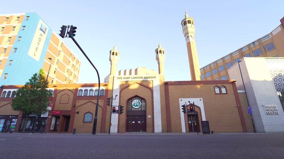 A mosque in a city with a blue building in the background
