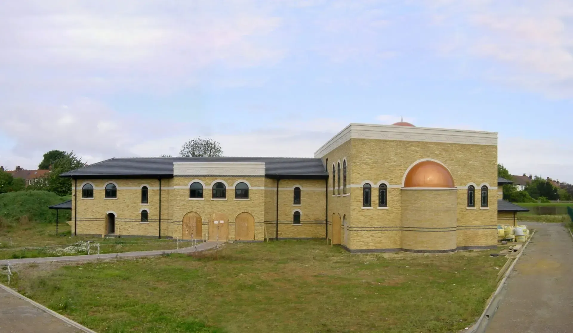 A large brick building is sitting in the middle of a grassy field.