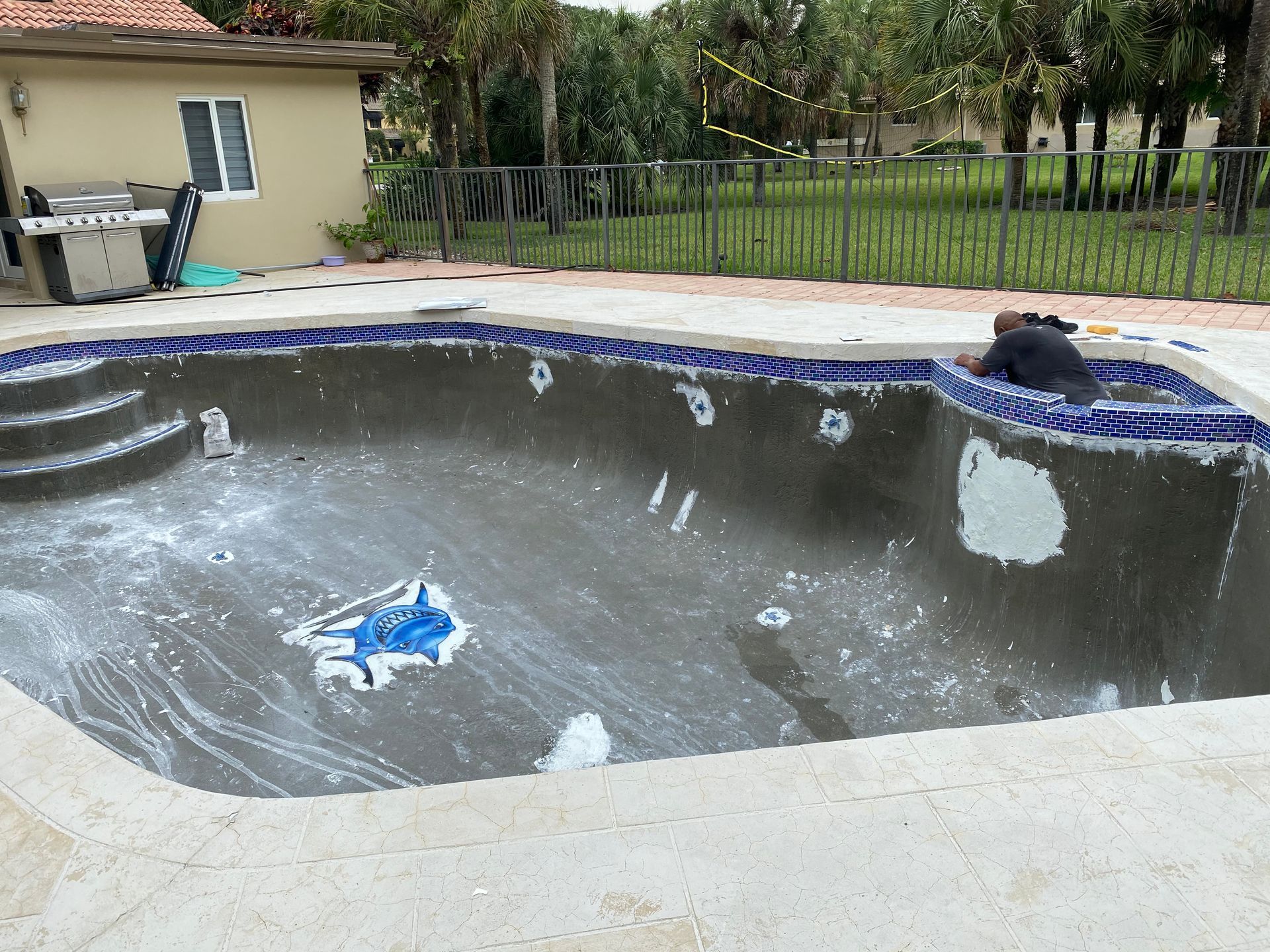 A man is working on a swimming pool in front of a house.