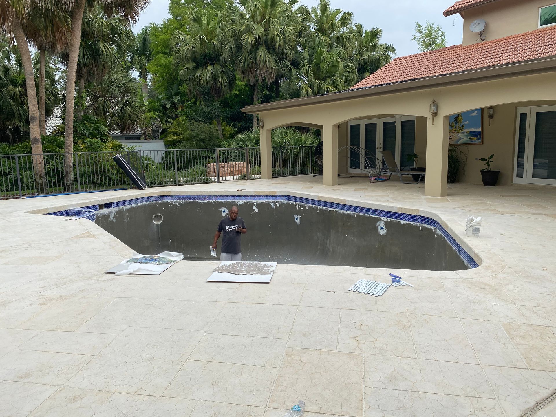 A man in a blue shirt is standing next to a swimming pool