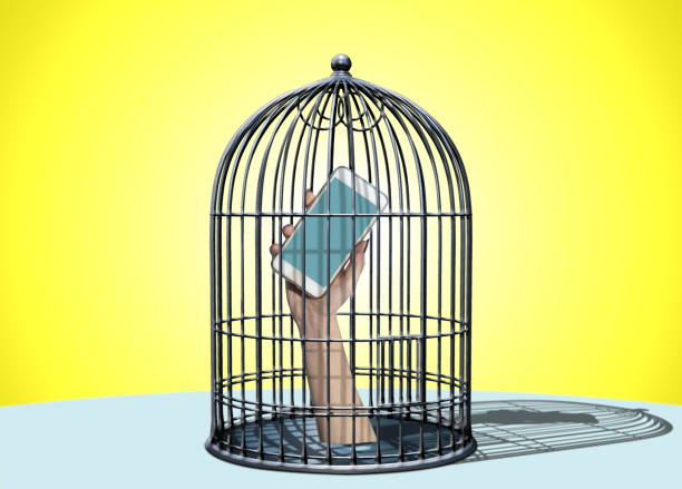 Hand holding smartphone inside a cage, symbolizing addiction to technology. Yellow background.
