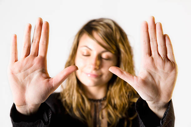 Woman with closed eyes frames face with outstretched hands.