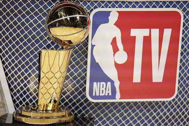 The Larry O'Brien NBA Championship Trophy sits beside the NBA TV logo against a blue and white patterned background.