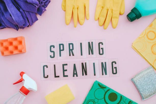 Spring cleaning supplies arranged on a pink background, with text that reads 