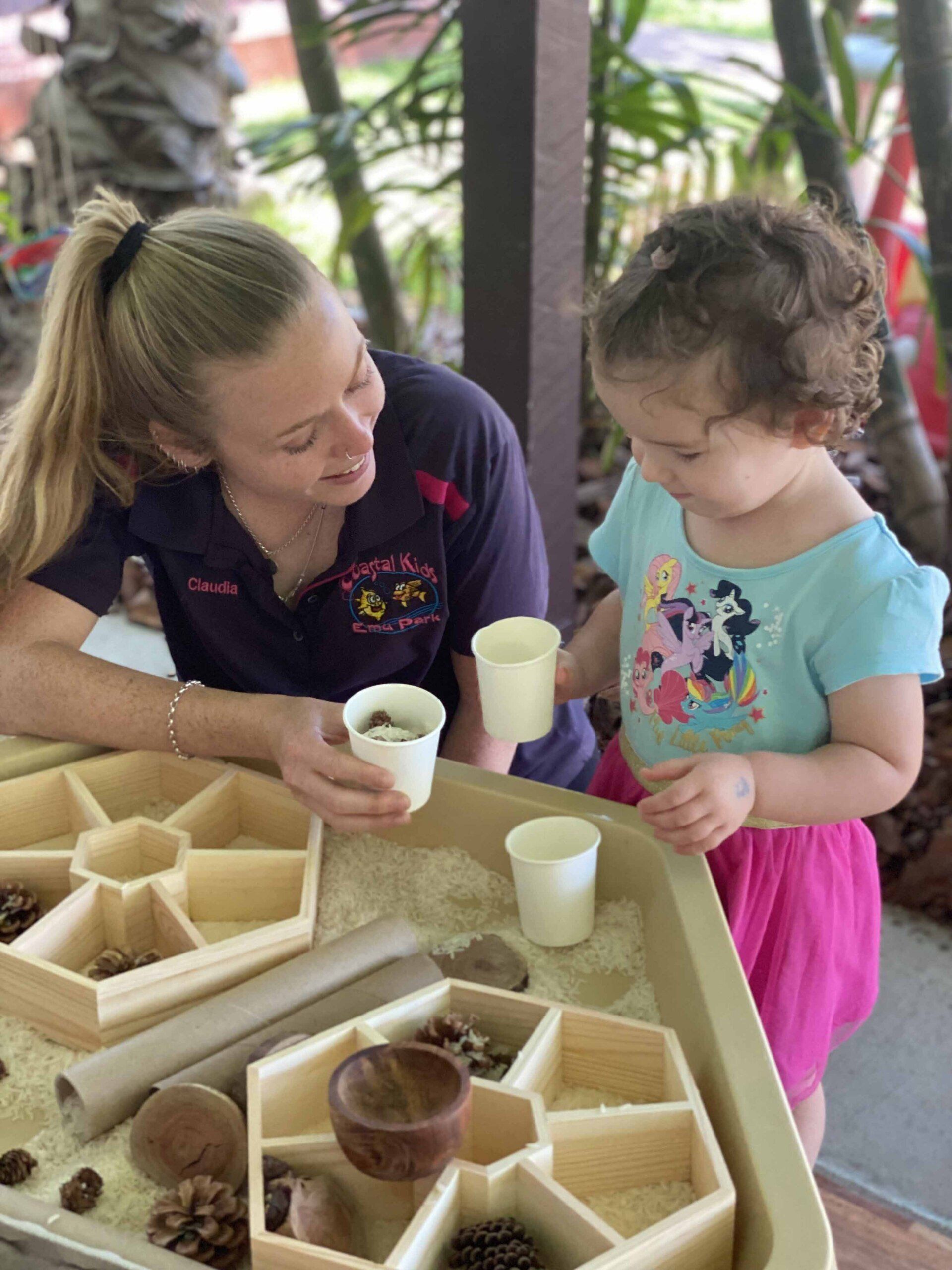 Teacher and Little Girl Playing Cups — Emu Park, QLD — Coastal Kids