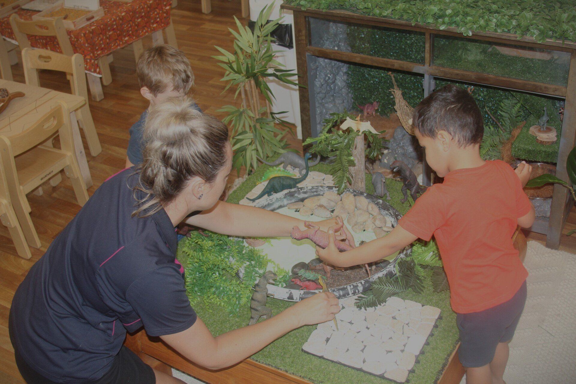 Teacher and Kids Playing Dinosaur Toys — Emu Park, QLD — Coastal Kids