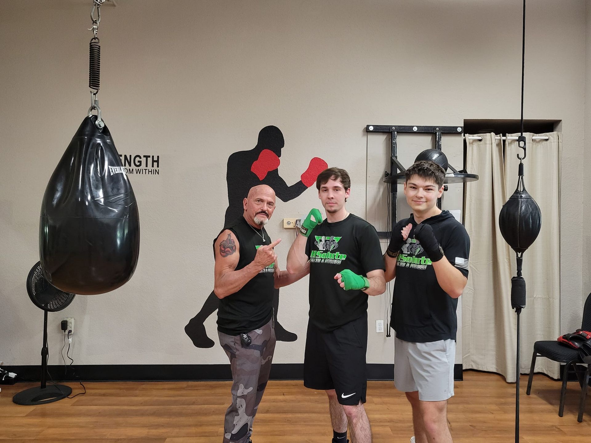 Three men are posing for a picture in a boxing gym.