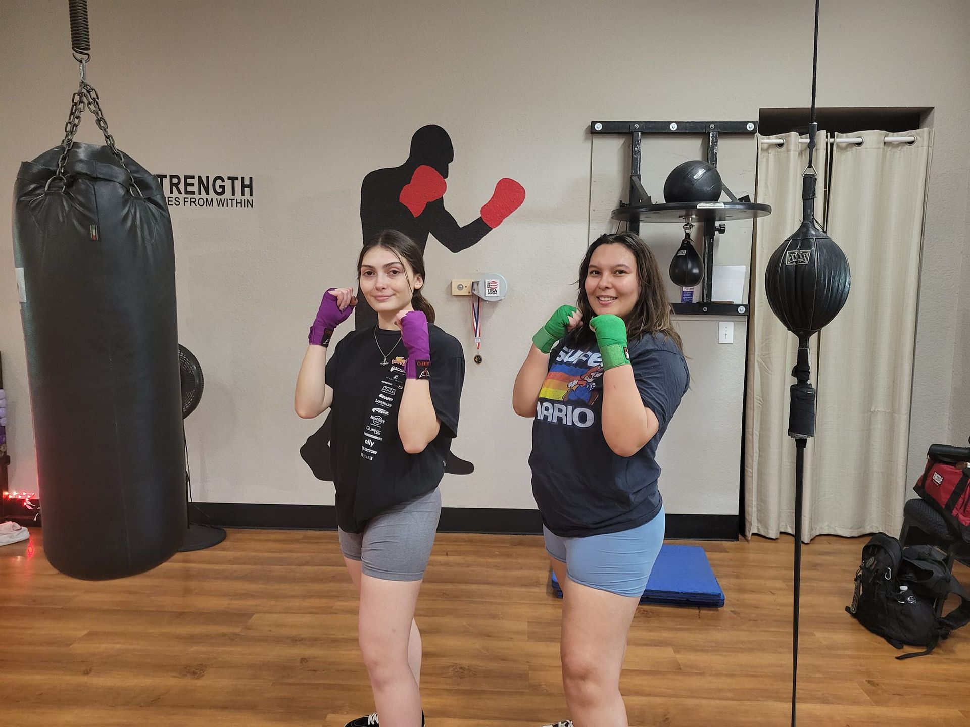 Two women are standing next to each other in a boxing gym.