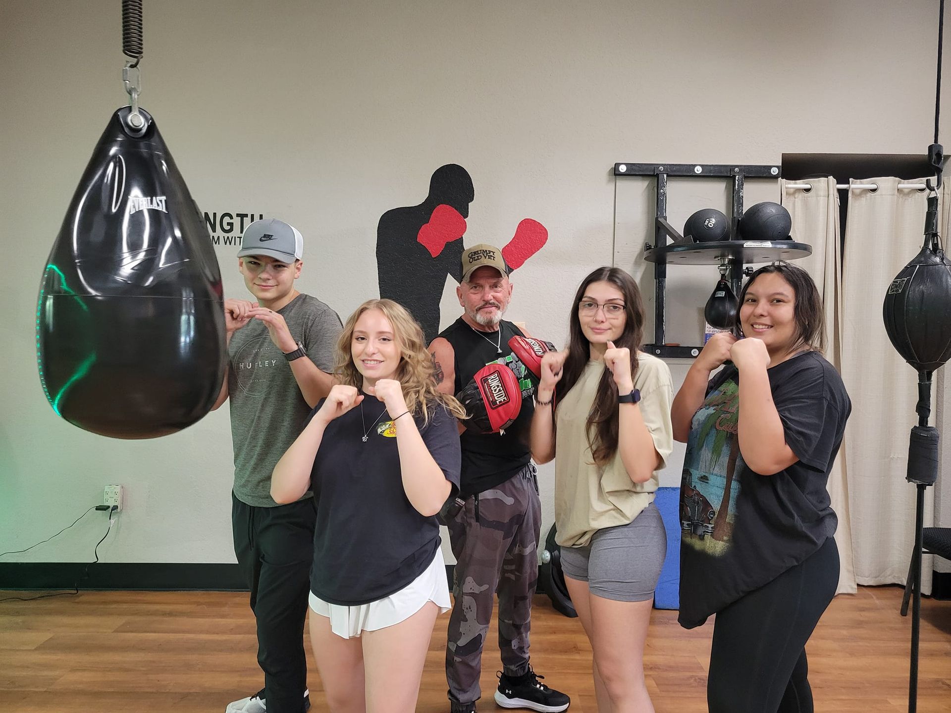 A group of people are posing for a picture in a boxing gym.