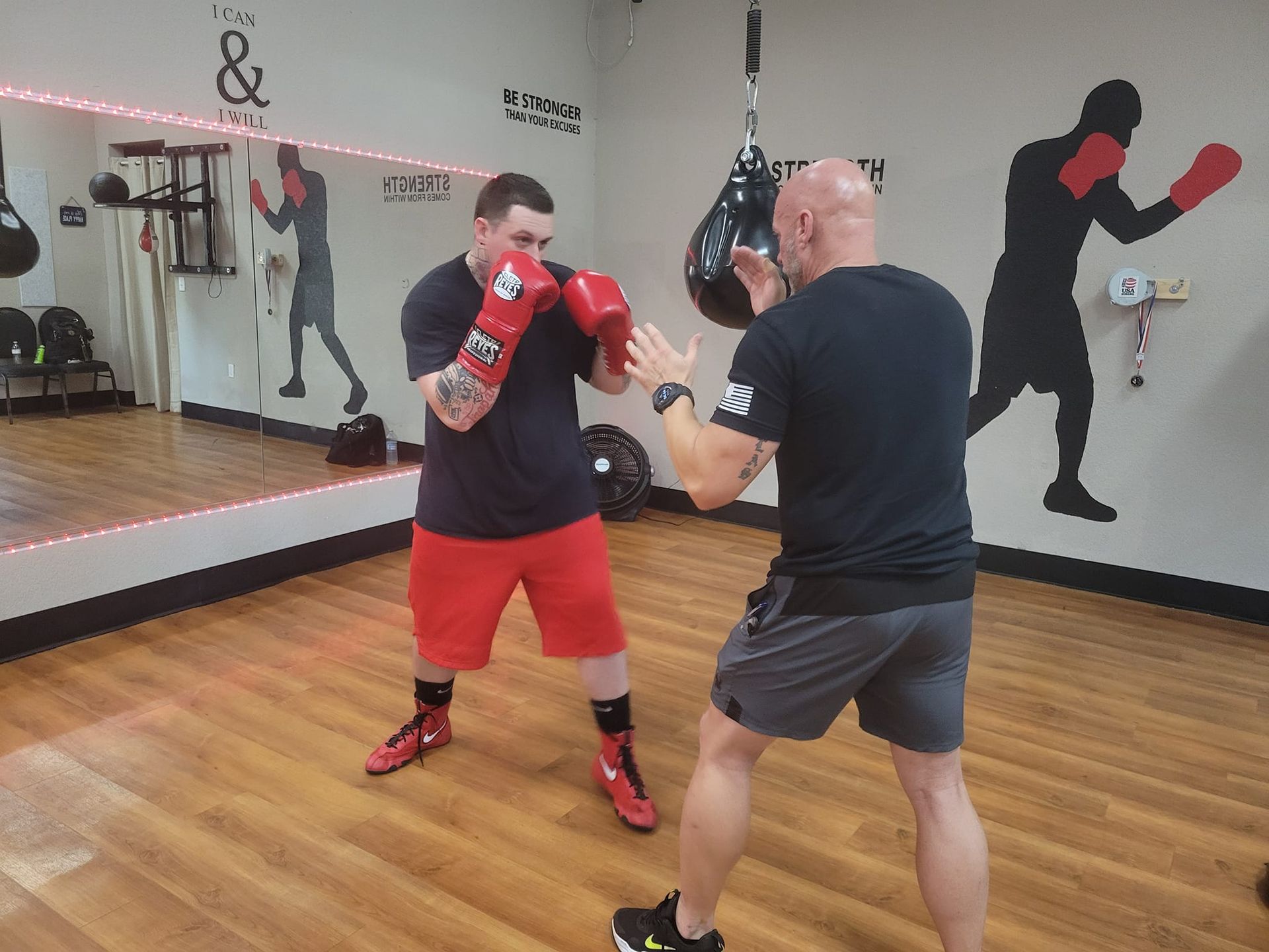 Two men are boxing in a gym in front of a mirror.