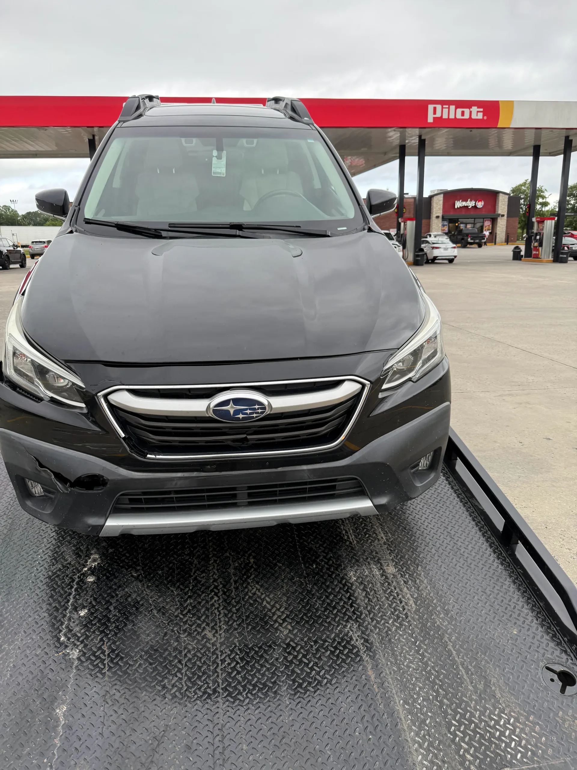 Gray Subaru SUV at a Pilot gas station in the rain, front view on a wet driveway