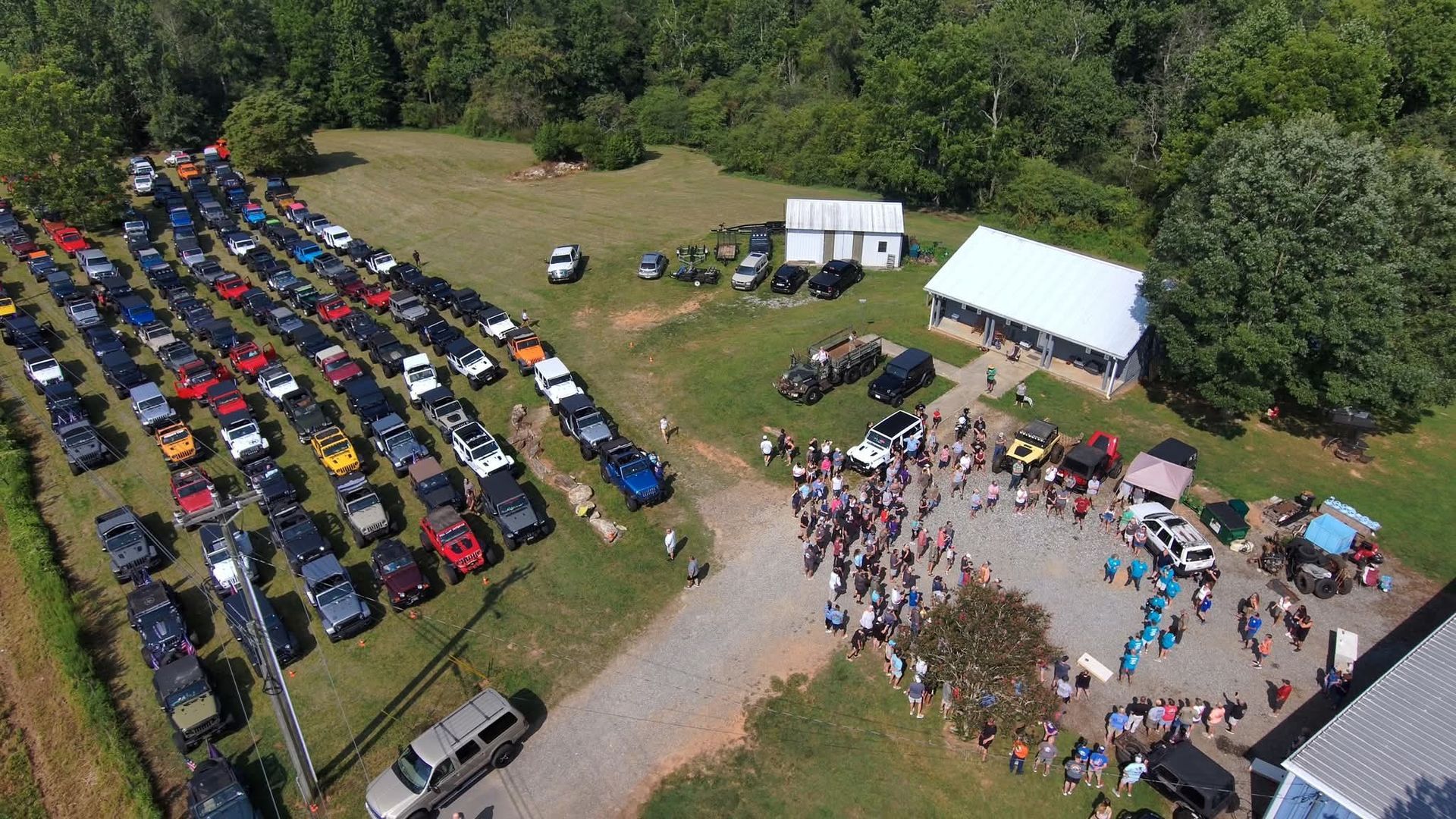 A group of jeep 's are parked on the side of a dirt road.