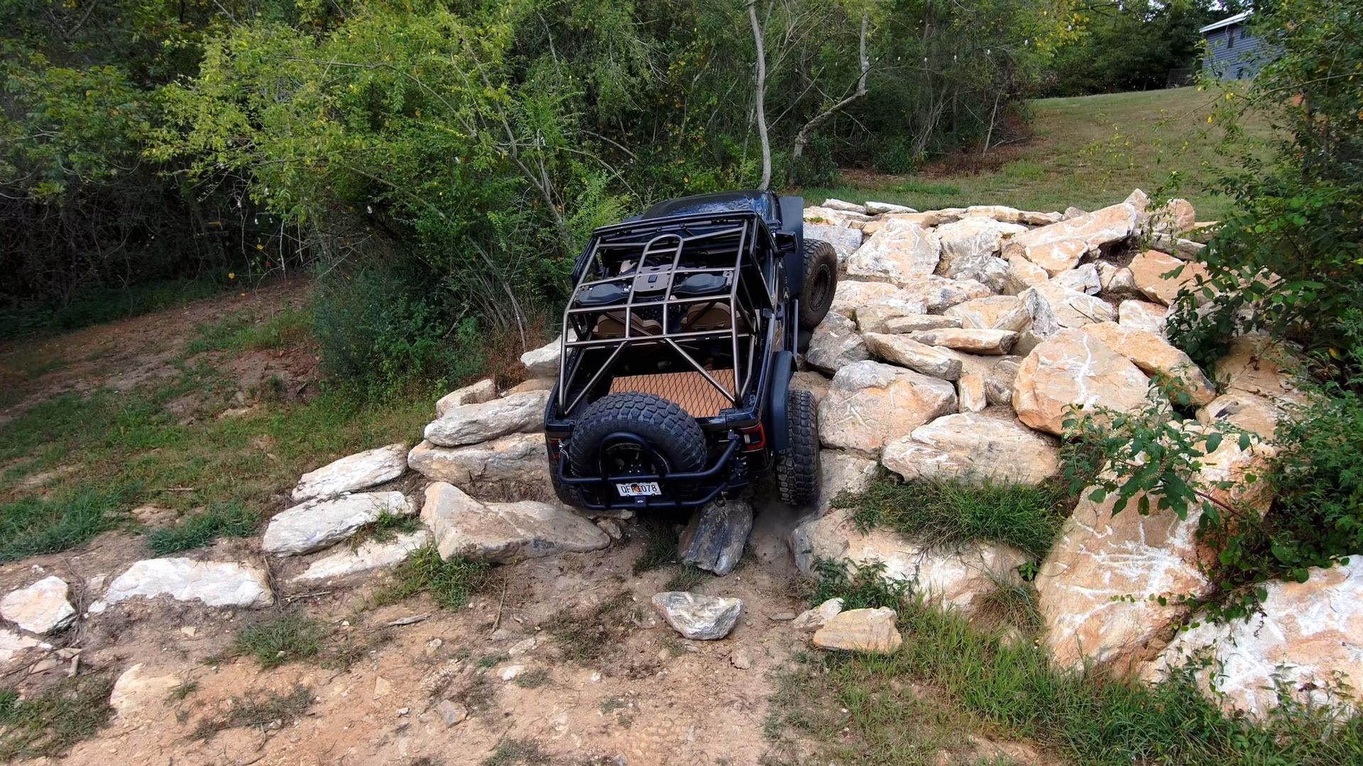 A jeep is driving through a rocky area in the woods.