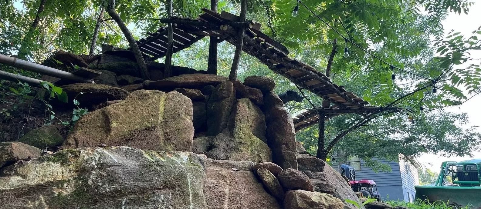 A waterfall is surrounded by rocks and trees in a park.