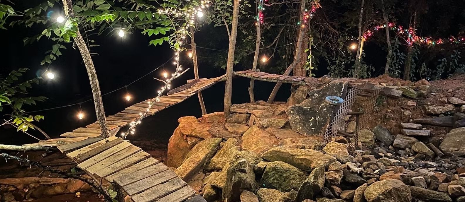 A wooden bridge in the middle of a forest at night.