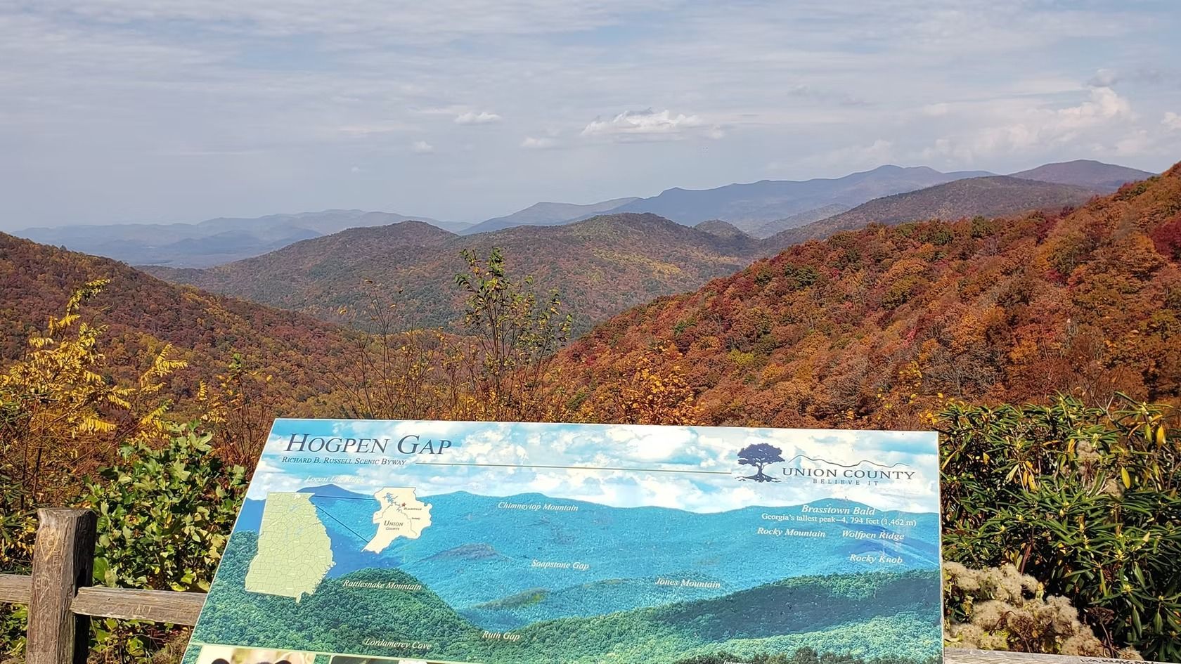 A sign with a picture of mountains and trees on it.