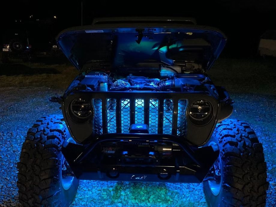 A jeep with the hood open is lit up with blue lights.